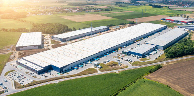 Mercado imobiliário corporativo: vista aérea de complexo logístico industrial de grande porte em área de expansão.