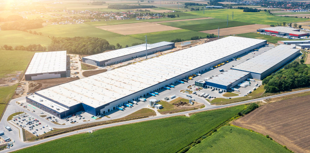 Mercado imobiliário corporativo: vista aérea de complexo logístico industrial de grande porte em área de expansão.