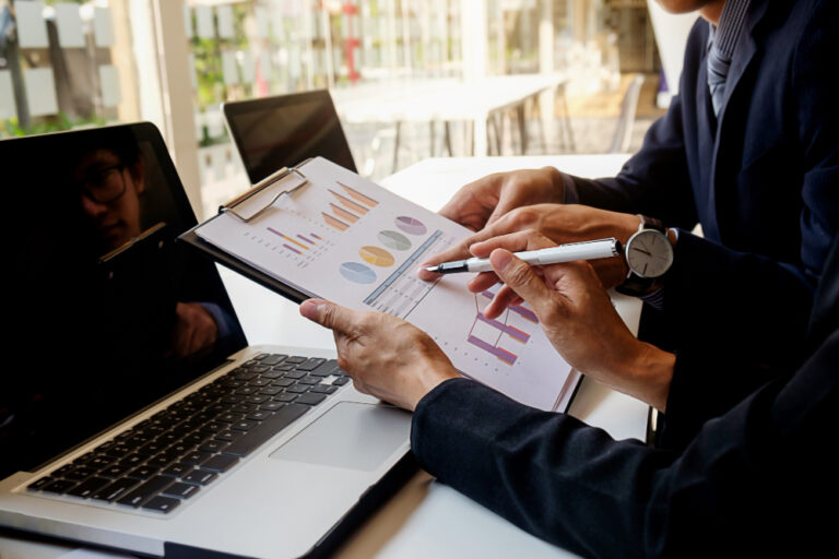 Gestora de recursos: executivos analisando relatório de performance e gráficos de alocação de ativos em reunião institucional
