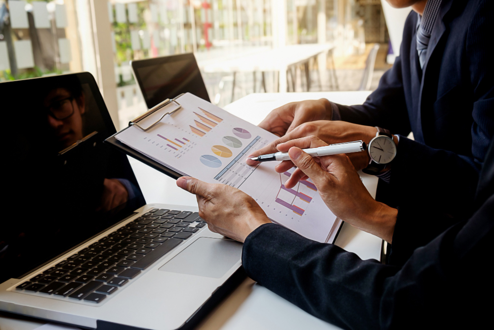 Gestora de recursos: executivos analisando relatório de performance e gráficos de alocação de ativos em reunião institucional